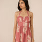 Woman wearing a pink dress with white floral patterns against a beige background Calling June