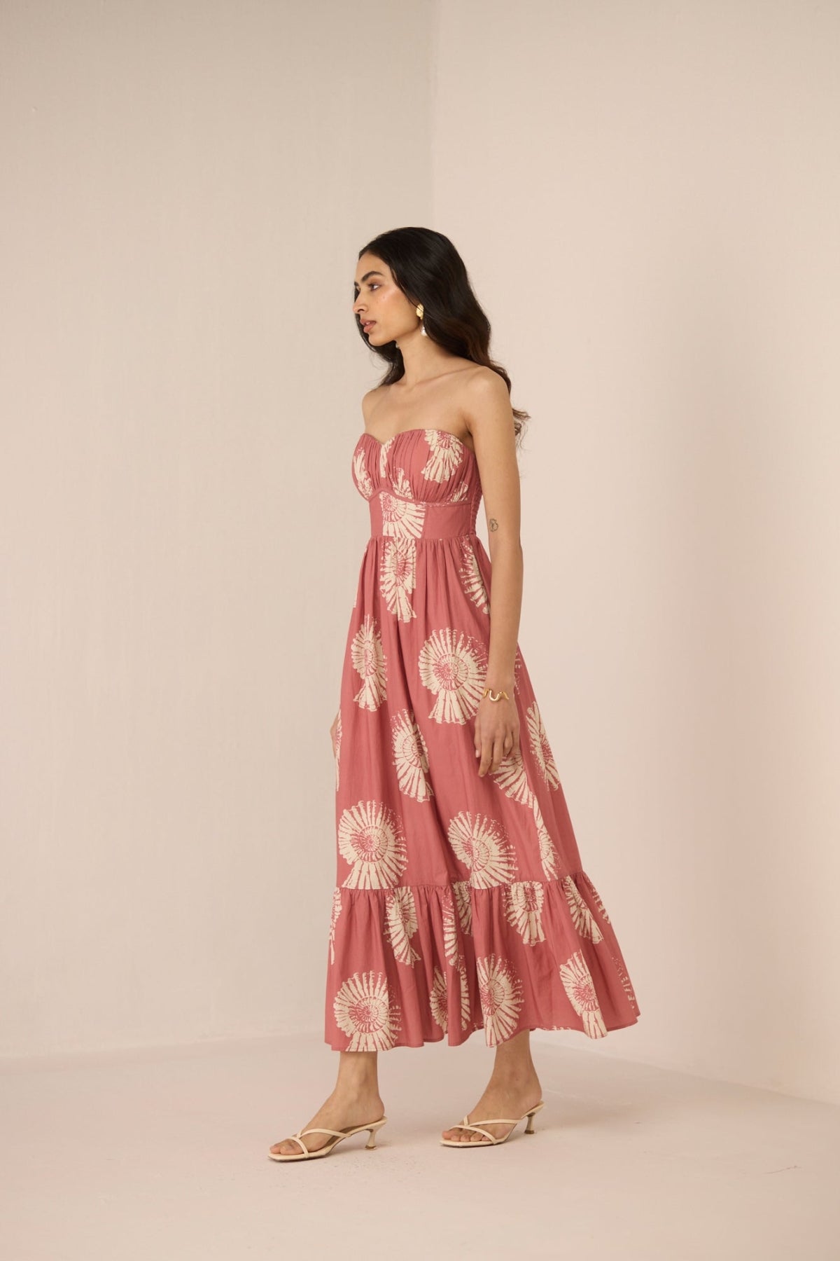 Woman wearing a pink strapless dress with white floral pattern on a beige background Calling June