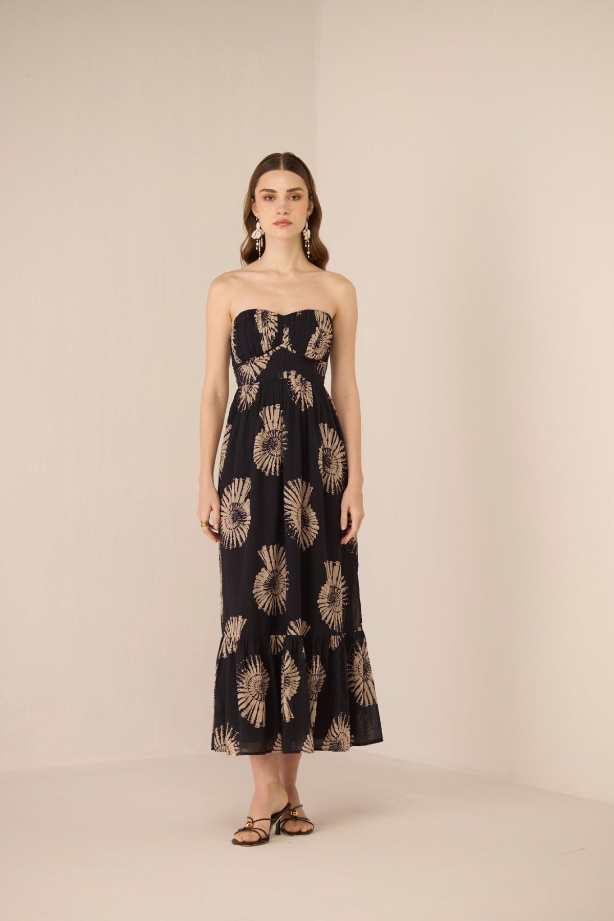 Woman wearing a strapless dress with floral pattern on a beige background Calling June