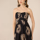 Woman wearing a strapless dress with sunflower pattern on a beige background Calling June