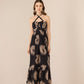 Woman wearing a black dress with gold floral patterns on a beige background Calling June