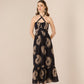Woman wearing a black dress with gold floral patterns on a beige background Calling June