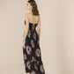 Woman wearing a black floral dress against a beige background Calling June
