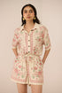 Woman wearing a floral romper against a plain background Calling June