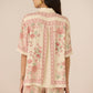 Woman wearing a floral patterned outfit on a beige background Calling June