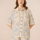 Woman wearing a floral patterned outfit on a beige background Calling June