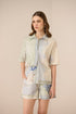 Woman wearing a patterned shirt and shorts on a beige background Calling June