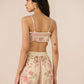 Woman wearing a floral top and shorts set on a beige background Calling June