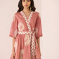 Woman wearing a pink dress with a geometric pattern on a plain background Calling June