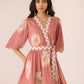 Woman wearing a pink patterned dress against a plain background Calling June