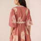 Woman wearing a pink dress with white patterns on a plain background Calling June