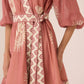 Pink and white patterned dress with long sleeves on a neutral background Calling June