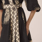 Black and beige patterned dress with a belt on a neutral background Calling June