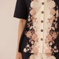 Floral patterned shirt with black, pink, and beige colors on a neutral background Calling June