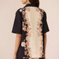Woman wearing a black and beige floral outfit against a beige background Calling June