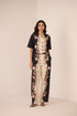 Woman wearing a black and white floral jumpsuit on a beige background Calling June
