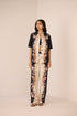 Woman wearing a black and white floral outfit on a beige background Calling June