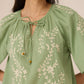 Green embroidered blouse worn by a person on a plain background Calling June