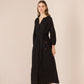 Woman wearing a black dress with buttons on a beige background Calling June