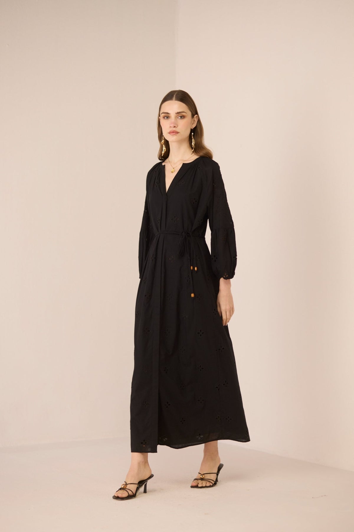 Woman wearing a black dress with buttons on a beige background Calling June