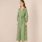Woman wearing a green dress with floral patterns against a beige background Calling June