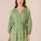 Woman wearing a green dress with floral embroidery against a beige background Calling June