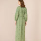 Woman wearing a green dress with floral patterns on a beige background Calling June