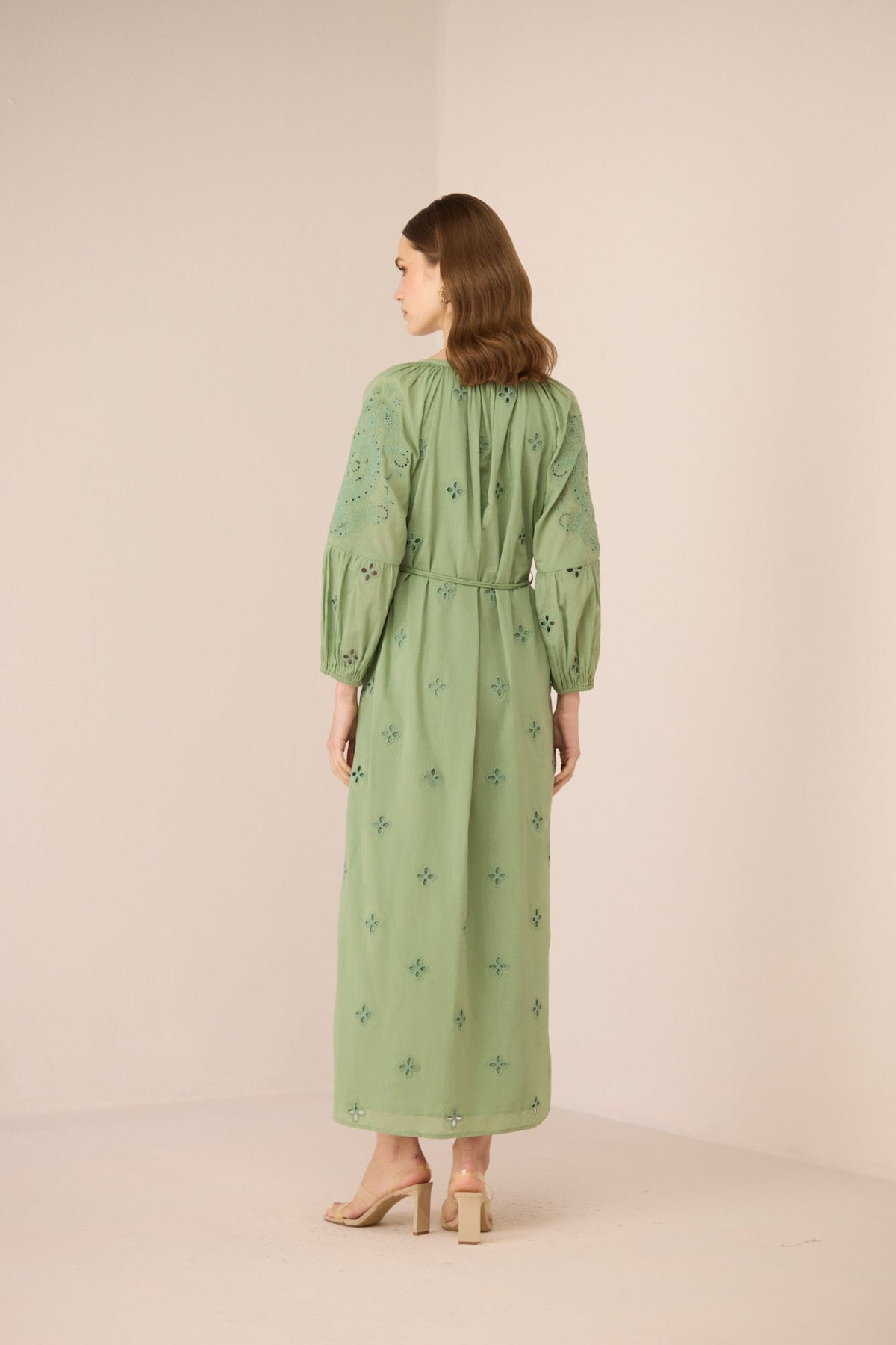Woman wearing a green dress with floral patterns on a beige background Calling June