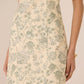 Beige dress with green floral pattern worn by a person on a beige background Calling June