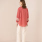 Woman wearing a pink blouse with floral embroidery and white pants on a beige background Calling June