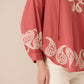 Red blouse with white embroidery on a beige background Calling June
