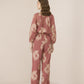 Woman wearing a pink floral outfit on a beige background Calling June