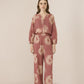 Woman wearing a pink floral jumpsuit on a beige background Calling June