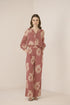 Woman wearing a pink floral jumpsuit on a beige background Calling June