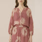 Woman wearing a pink floral dress against a beige background Calling June