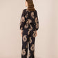 Woman wearing a black floral patterned outfit on a beige background Calling June