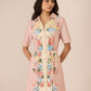 Woman wearing a pink floral dress against a beige background Calling June