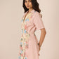 Woman wearing a pink floral robe against a beige background Calling June