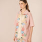 Woman wearing a pink floral outfit against a beige background Calling June