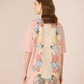 Woman wearing a floral kimono-style garment with a plain background Calling June