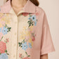 Woman wearing a floral blouse with a soft pink background Calling June