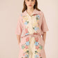 Woman wearing a pink floral outfit on a beige background Calling June