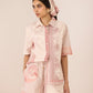 Woman wearing a pink and white patterned outfit with a matching headscarf against a beige background Calling June