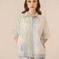 Woman wearing a light green and beige floral patterned shirt with matching shorts on a beige background Calling June
