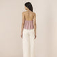 Woman wearing a patterned top and white pants on a beige background Calling June