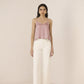 Woman wearing a pink top and white pants on a plain background Calling June