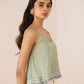 Woman wearing a green patterned top with a beige background Calling June