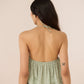 Woman wearing a green halter top with a beige background Calling June