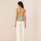 Woman wearing a green top and white pants on a beige background Calling June