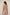 Woman wearing a pink checkered romper with tassel details on a beige background Calling June
